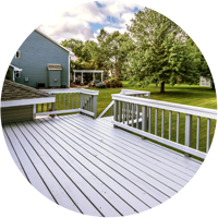 A deck with white railing and blue siding.